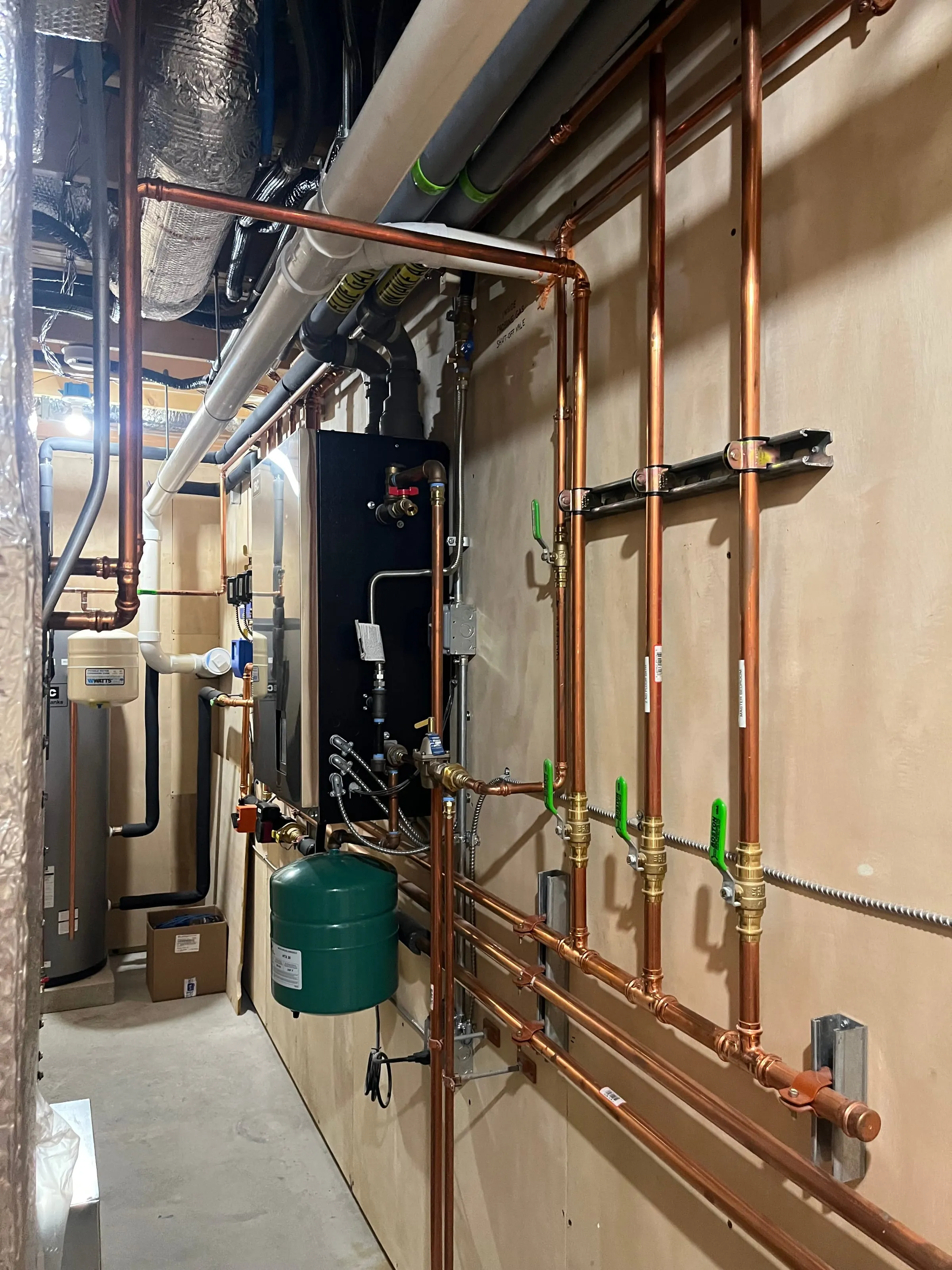 Boiler room with labeled copper supply and return lines, shutoff valves, and expansion tank