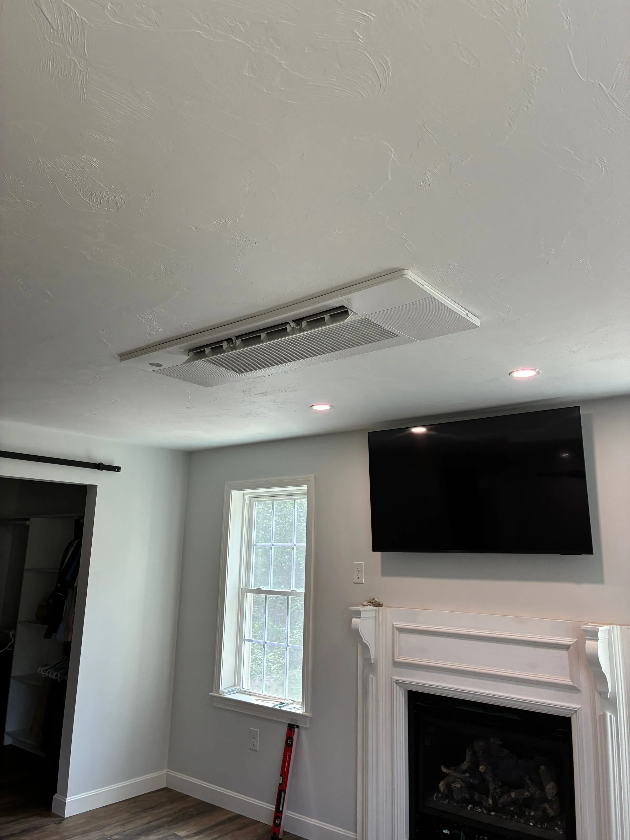 Ceiling cassette heat pump installed in a living room with fireplace