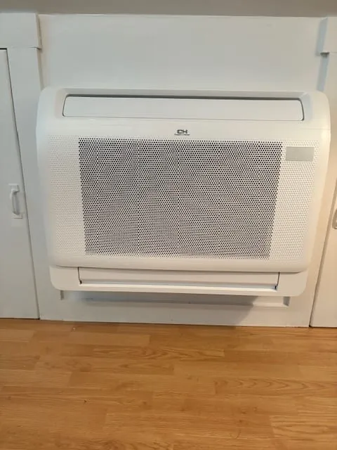 Floor console heat pump unit installed low on a wall