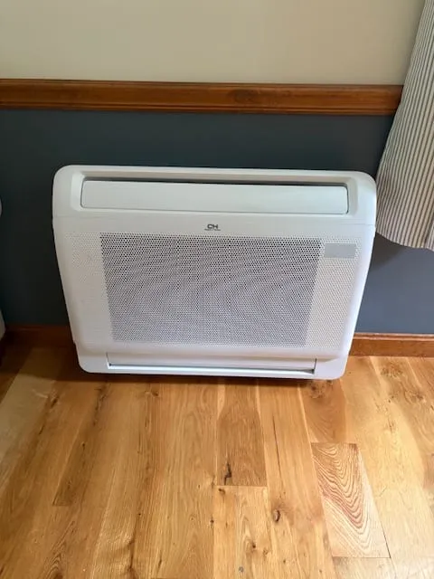Floor console heat pump installed in a room with hardwood flooring