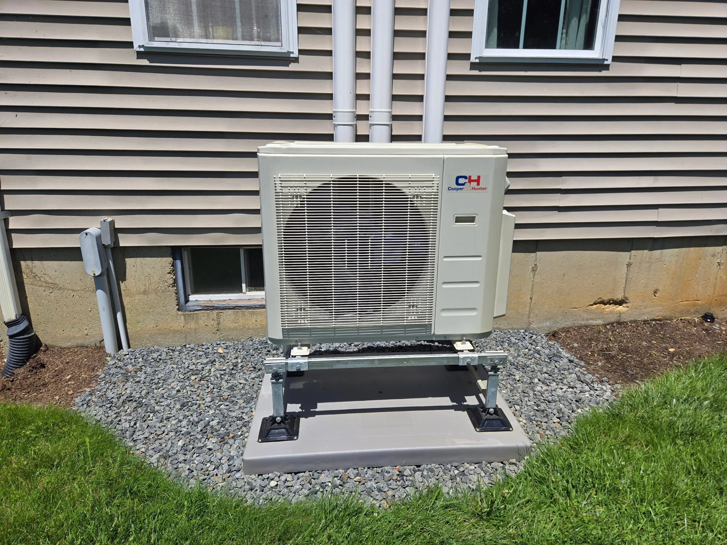 Heat pump outdoor condenser installed on a level ground pad with gravel base