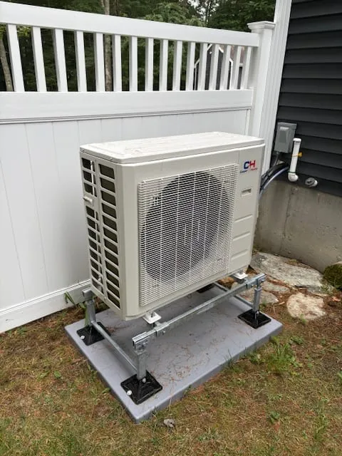 Heat pump outdoor unit installed in a side yard beside a fence