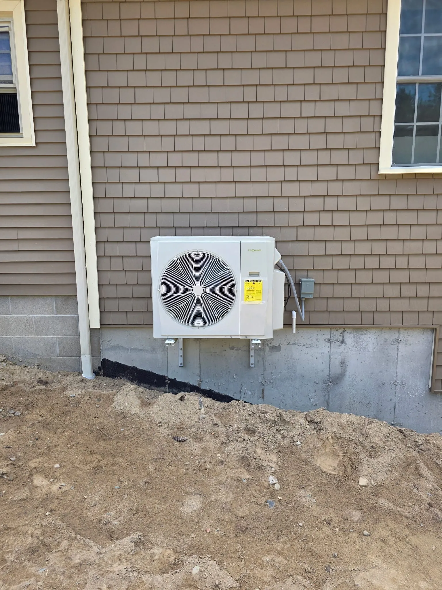Heat pump outdoor unit mounted on wall brackets above grade