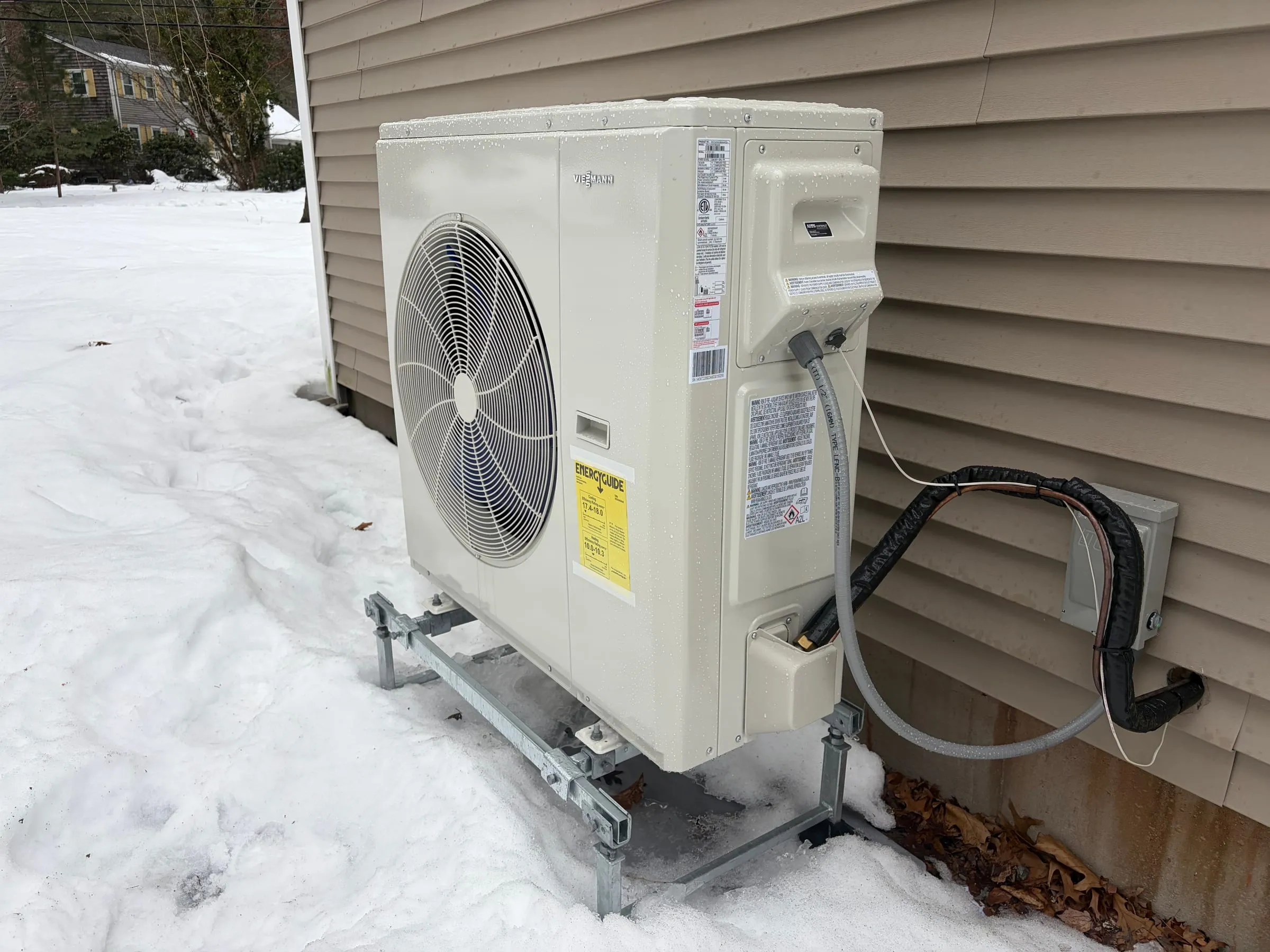 Cold-climate heat pump running outdoors in New England snow